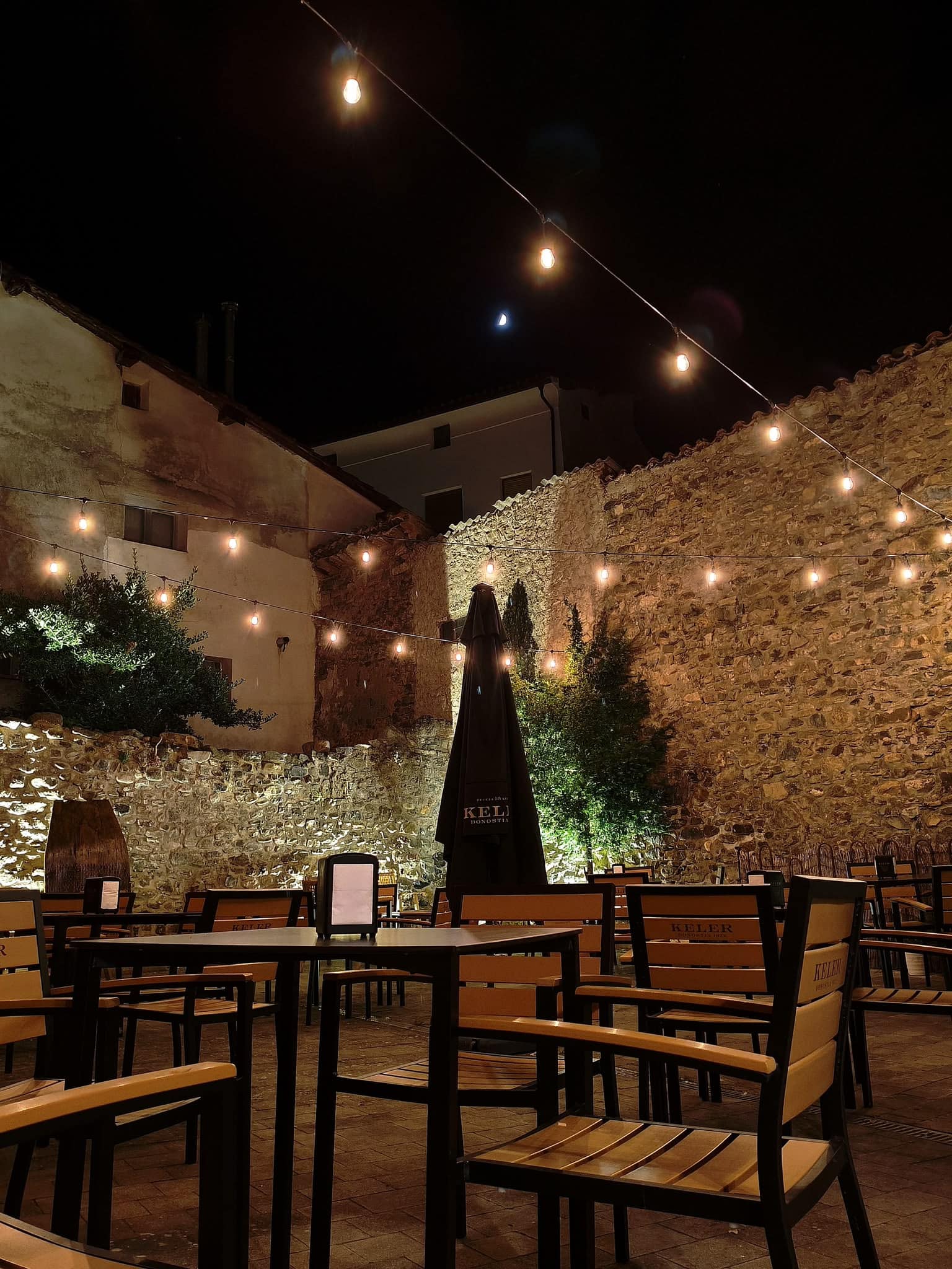 Terraza del restaurante Posada Santa Rita con iluminación nocturna y mobiliario de madera.